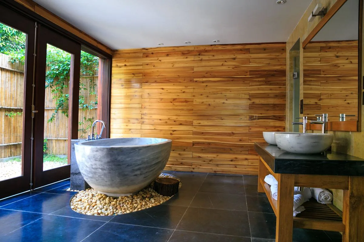 Salle de bains en bois et pierre avec baignoire sculptée — Chambre Deluxe Vue Océan, Hôtel Olympe Libreville