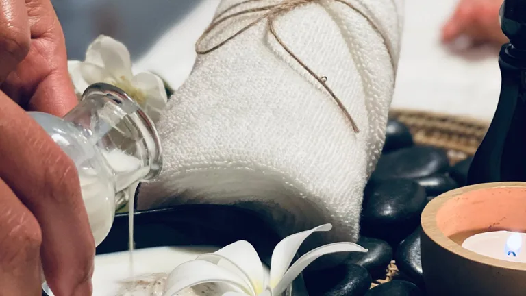 Huile de moabi versée avant un massage, fleurs de frangipanier